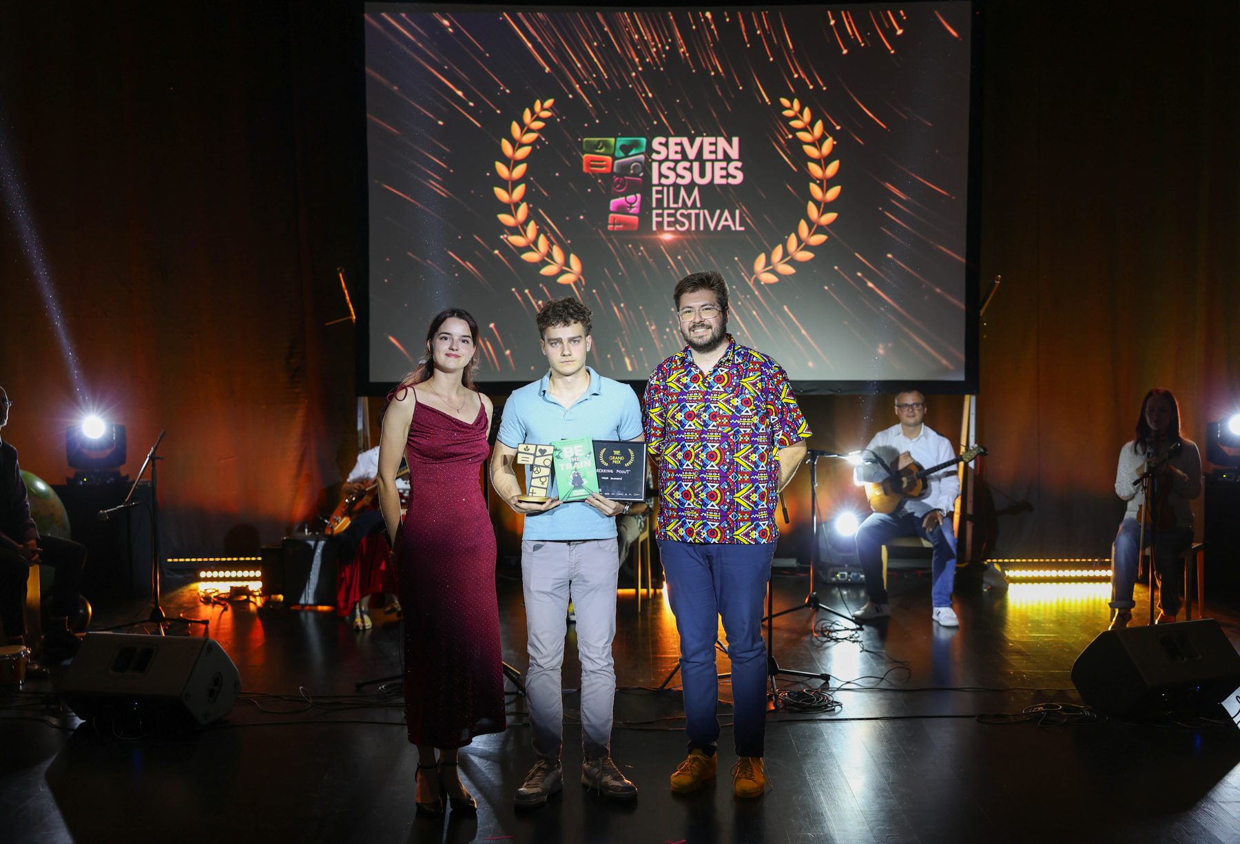 Award winners holding their prizes on the Edison Cinema stage.